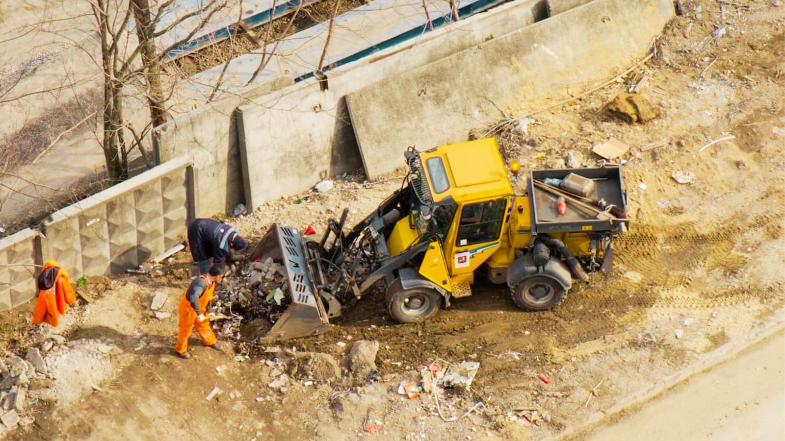 Workers manually clearing brush and debris using hand tools.